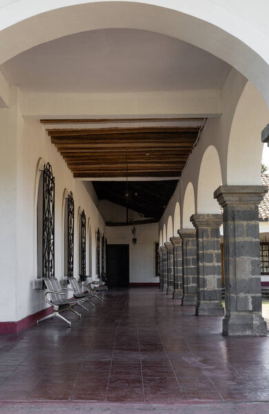 Элегантный колониальный коридор в эквадорской гасиенде с каменными арками, деревянным потолком и историческим шармом, отражающим культурное наследие и сельскую традицию.