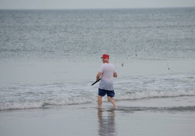 Sahilde balıkçı teknesi olan bir balıkçı.