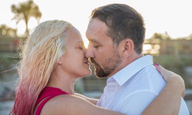 Sahilde gün batımında romantik çift öpücüğü.