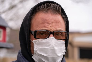 Coronavirus sırasında gözlük ve tıbbi maske takan beyaz bir adam.