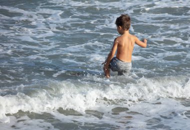 Sahilde mayo giymiş bir çocuk.