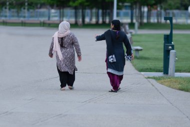 Bilinmeyen Orta Doğulu kadınlar gün batımında parkta yürüyorlar.