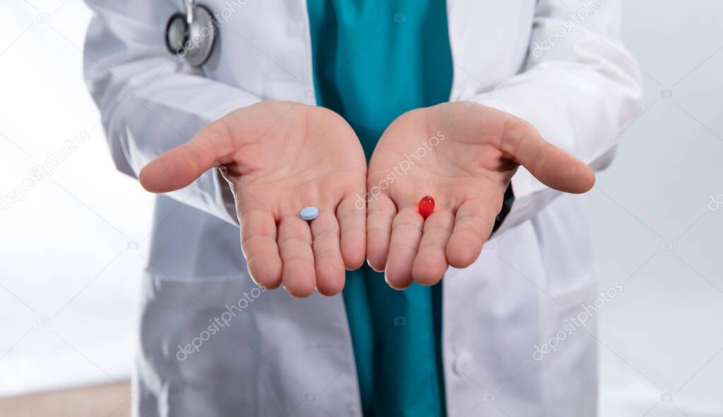 doctor hands hold a red pill and a blue pill