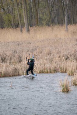 Harrison Township, Michigan, ABD - 02 Mayıs 2020: Uçurtma sörfçüleri ve rüzgar sörfçüleri Michigan Metro Parkı 'nda rüzgarlı bir günde pratik yapıyorlar.