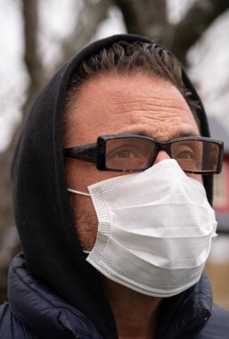 Coronavirus sırasında gözlük ve tıbbi maske takan beyaz bir adam.