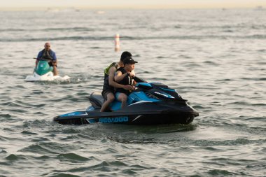 Kişisel su araçları güneşli bir günde Metro Parkı 'nda eğleniyor ve numaralar yapıyor.