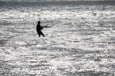 Harrison Township, Michigan, ABD - 02 Mayıs 2020: Uçurtma sörfçüleri ve rüzgar sörfçüleri Michigan Metro Parkı 'nda rüzgarlı bir günde pratik yapıyorlar.