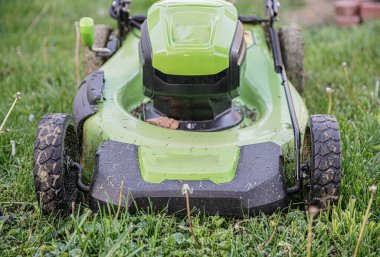 Pille çalışan çim biçme makinesi gaz kullanmadan uzun otları kesiyor.