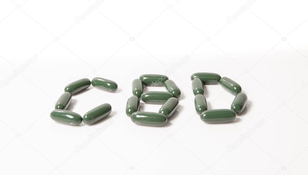 green pills spell CBD on a white background
