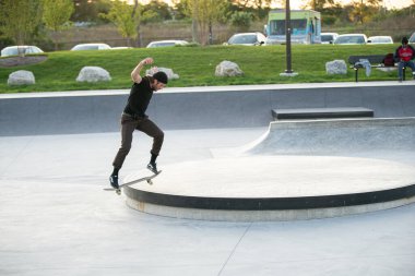 Detroit, Michigan, ABD - 10.07.2019: Patenciler ve motosikletçiler Detroit 'teki kaykay parkında gün batımında numara yapıyorlar