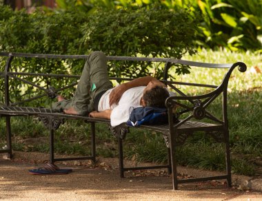 Bilinmeyen bir adam güneşli bir günde parkta uyuyor.