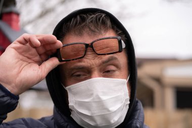 Coronavirus sırasında gözlük ve tıbbi maske takan beyaz bir adam.