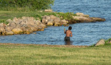 Bilinmeyen bir çocuk, güneşli bir günde bir su topuyla eğleniyor.