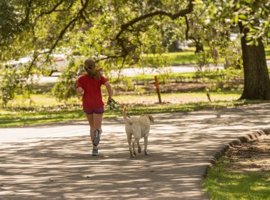 Bilinmeyen koşucu, köpeğini parkta koşuya çıkarıyor.