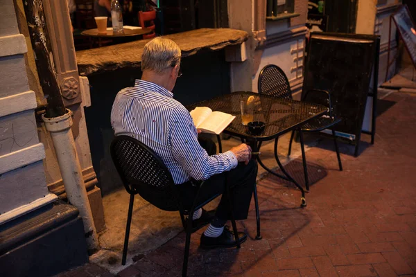 Ανώτερος Άνθρωπος Κάθεται Στο Τραπέζι Και Διαβάζοντας Βιβλίο — Φωτογραφία Αρχείου