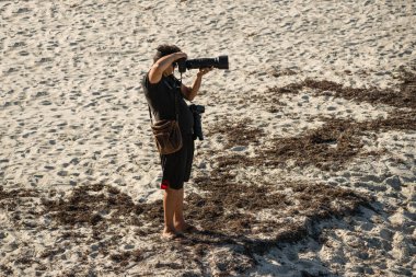 Sahilde kameralı bir fotoğrafçı.
