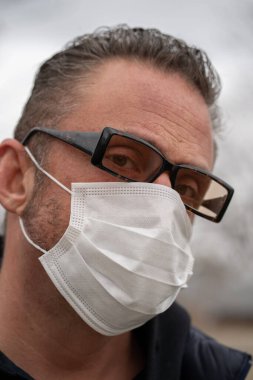Coronavirus sırasında gözlük ve tıbbi maske takan beyaz bir adam.