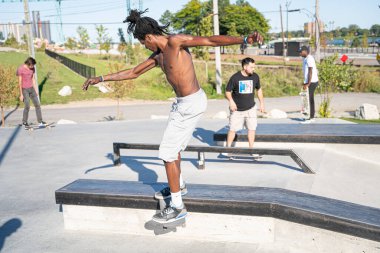 Detroit 'te güneşli bir öğleden sonra, açık hava kaykay pistinde patenciler...