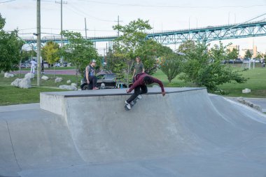 Patenciler ve motorcular numaralarını güneşli bir yaz gününde halka açık olan açık bir kaykay parkında yapıyorlar.