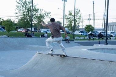 Patenciler ve motorcular numaralarını güneşli bir yaz gününde halka açık olan açık bir kaykay parkında yapıyorlar.