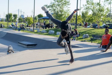 Patenciler ve motorcular numaralarını güneşli bir yaz gününde halka açık olan açık bir kaykay parkında yapıyorlar.