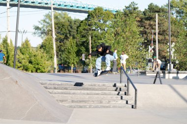 Patenciler ve motorcular numaralarını güneşli bir yaz gününde halka açık olan açık bir kaykay parkında yapıyorlar.