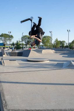 Patenciler ve motorcular numaralarını güneşli bir yaz gününde halka açık olan açık bir kaykay parkında yapıyorlar.