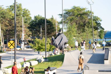 Patenciler ve motorcular numaralarını güneşli bir yaz gününde halka açık olan açık bir kaykay parkında yapıyorlar.