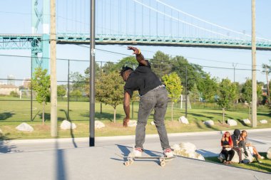 Patenciler ve motorcular numaralarını güneşli bir yaz gününde halka açık olan açık bir kaykay parkında yapıyorlar.