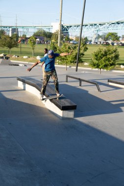 Patenciler ve motorcular numaralarını güneşli bir yaz gününde halka açık olan açık bir kaykay parkında yapıyorlar.