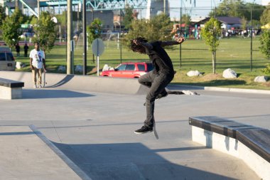 Patenciler ve motorcular numaralarını güneşli bir yaz gününde halka açık olan açık bir kaykay parkında yapıyorlar.