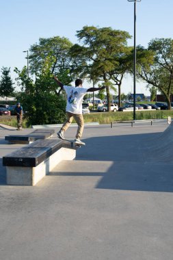 Patenciler ve motorcular numaralarını güneşli bir yaz gününde halka açık olan açık bir kaykay parkında yapıyorlar.