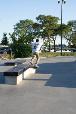 Patenciler ve motorcular numaralarını güneşli bir yaz gününde halka açık olan açık bir kaykay parkında yapıyorlar.