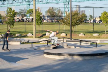 Patenciler ve motorcular numaralarını güneşli bir yaz gününde halka açık olan açık bir kaykay parkında yapıyorlar.