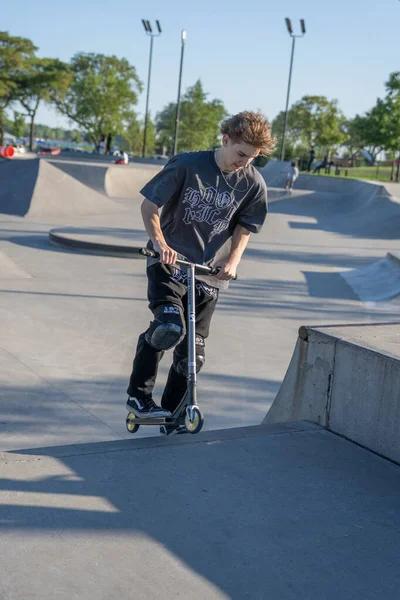 Patenciler ve motorcular numaralarını güneşli bir yaz gününde halka açık olan açık bir kaykay parkında yapıyorlar.