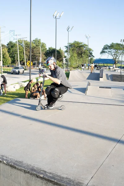 Patenciler ve motorcular numaralarını güneşli bir yaz gününde halka açık olan açık bir kaykay parkında yapıyorlar.