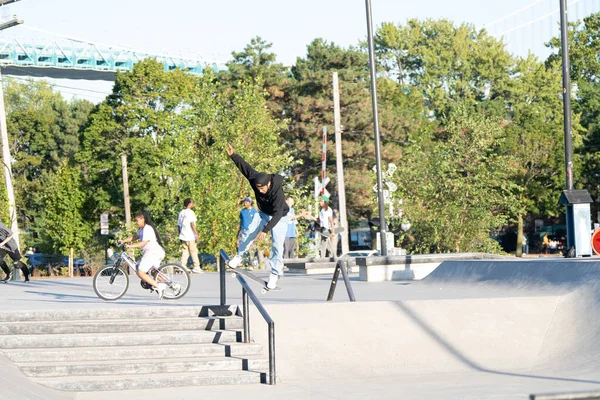 Patenciler ve motorcular numaralarını güneşli bir yaz gününde halka açık olan açık bir kaykay parkında yapıyorlar.