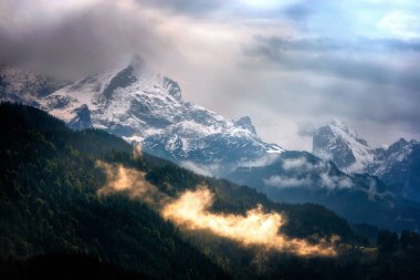 Wetterstein dağ manzaralı kış akşam sırasında. Dramatik bulutlu gökyüzü. Tipik sisli atmosfer. Bavyera Alpleri, Bavyera, Almanya'nın karlı zirveleri.