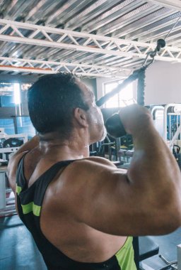 Ter içindeki olgun bir adam spor yapıyor, yan görüş, halat kablosu itme...