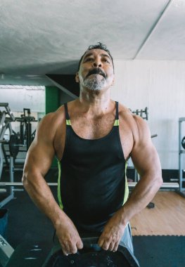 Olgun adam spor salonunda omuz egzersizi yapıyor, kaslı adam.