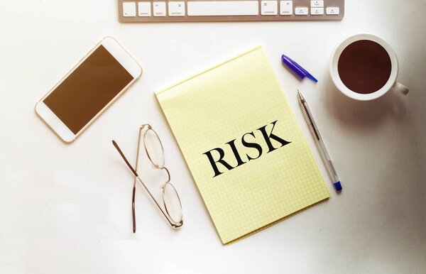 РИСК текст на желтой бумаге с телефоном, кофе, ручкой
