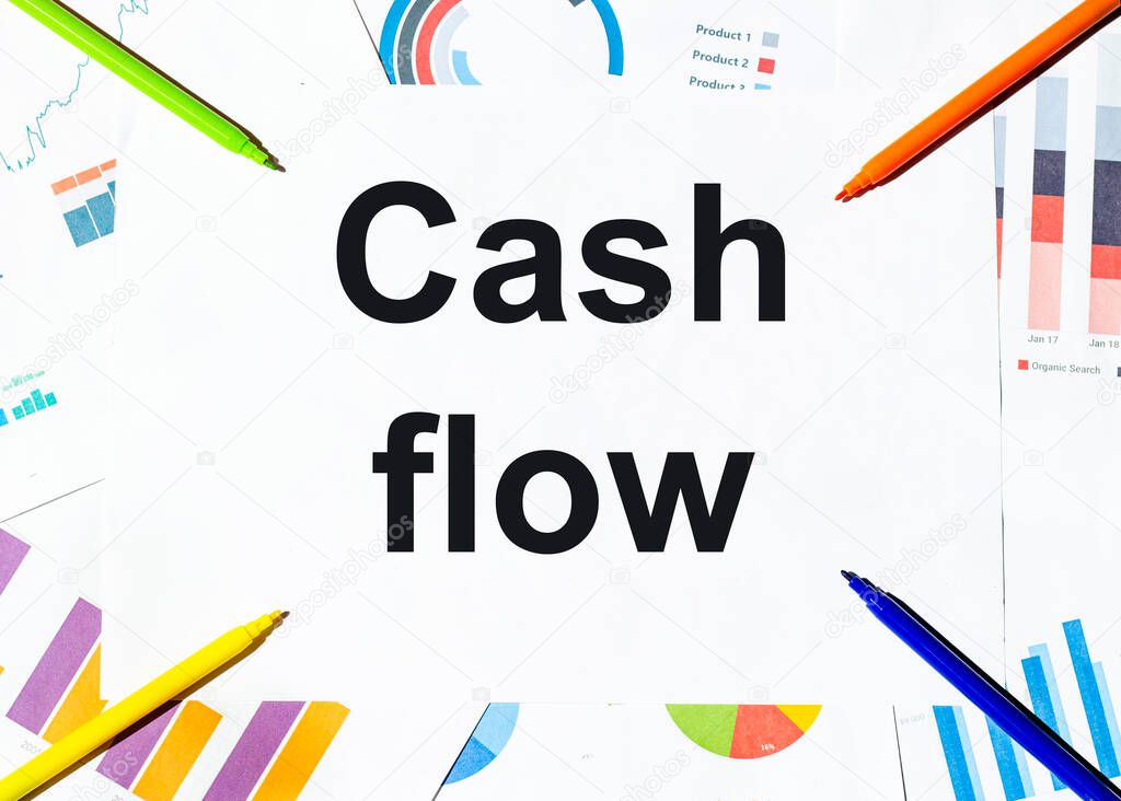 white piece of paper with text Cash flow on the background of the graphs, multi-colored felt-tip pens