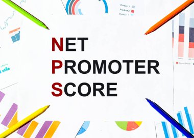 Grafiklerin arka planında NPS NET PROMOTER SCORE yazılı beyaz kağıt parçası, çok renkli keçeli kalemler