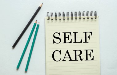 iki yeşil bir siyah kalem beyaz arka planda not defterinde kendine dikkat et.