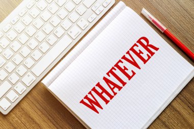 Üzerinde yazı olan beyaz bir defter. Üzerinde kırmızı işaretli beyaz bir klavyenin yanında duran tahta bir yüzey.