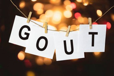 Metni Gout olan beyaz kağıt parçaları çok renkli bir bokeh arka planına karşı bir ipe asılmış.