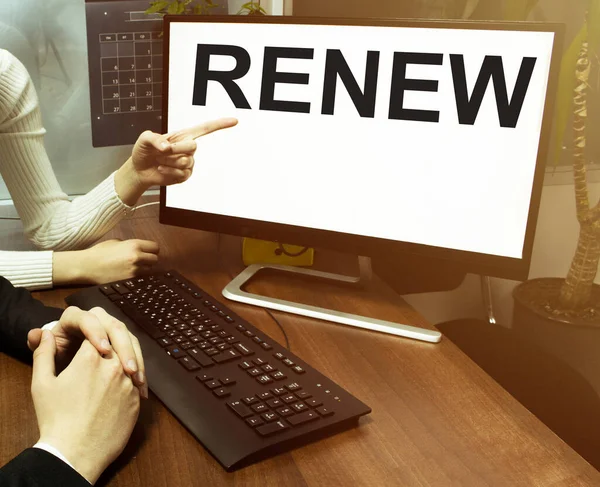 male and female hand, computer with text Renew with office background