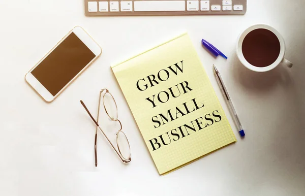 Grow Your Small Business text on the yellow paper with phone, coffee, pen