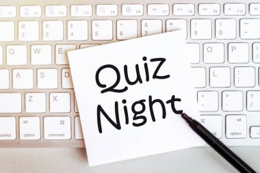 Siyah keçeli kalemle beyaz arkaplandaki klavyede metin Quiz Gecesi yazılı kağıt parçası