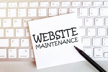 Klavyede siyah keçeli kalemle beyaz arkaplan üzerinde metin web sitesi bakımı olan bir kağıt parçası